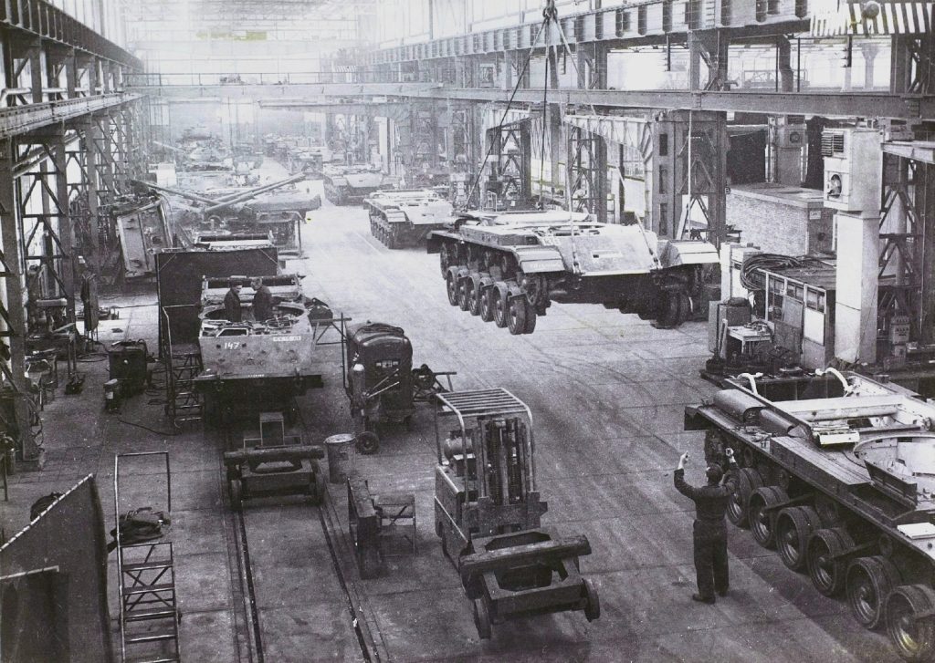 In de werkplaats van 574 Tankwerkplaats wordt de romp van een Centurion verplaatst met een bovenllopkraan