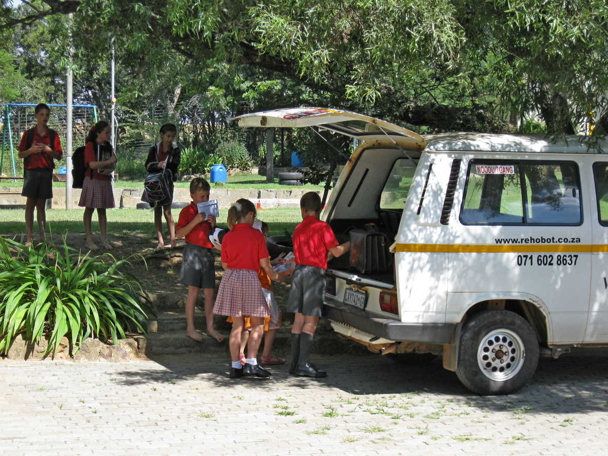 De Rehobotskool gaat uit. Kinderen verzamelen zich bij het busje om naar huis gebracht te worden.