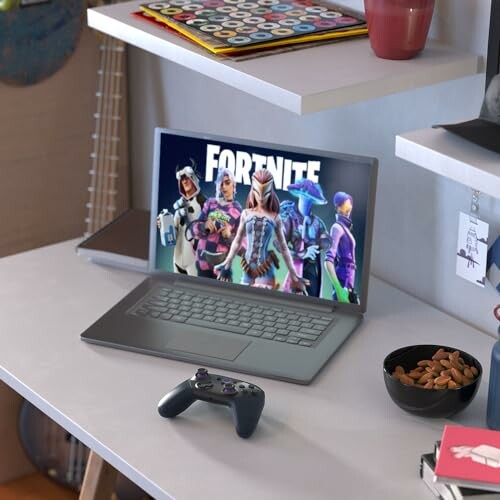 Laptop mit Fortnite-Spiel auf einem Schreibtisch, neben einem Controller und Snackschale.